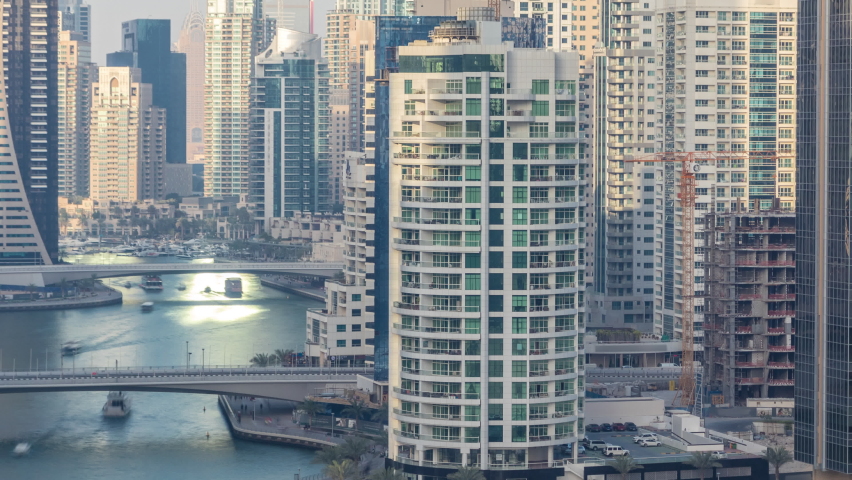 Amazing colorful dubai marina skyline during sunset timelapse. Great perspective of multiple tallest skyscrapers with yachts and boats on canal. Sunlight over buildings. United Arab Emirates.