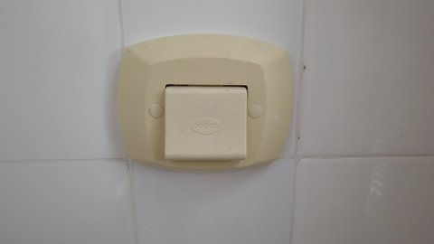 Teresopolis, RJ, Brazil - March 20th 2022 - Male hand pressing a plastic flush button on the wall. Flushing poop and pee, cleaning the bathroom. Sanitary flush.