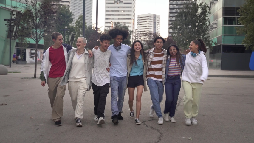 Group of multiracial carefree gen z friends embracing each other and walking together in the city. Youth diversity