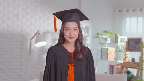 An Asian girl shows her certificate. She is greetings on her graduation ceremony. She is extremely happy on her successful and  achievement moment. She is so lively on her gown and obviously cheerful.