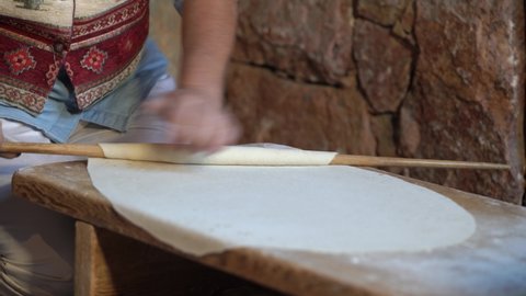 Armenian  bread (Lavash, Pita, Flatbread ) preparing process. The female's hands roll the thin dough on wooden table. Armenian traditions. Pita bread, Flatbread, Armenian national bread lavash.