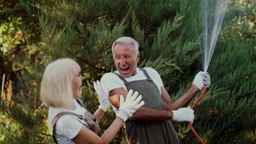Cheerful Senior Couple Having Fun In Garden, Happy Elderly Spouses Playing With Water Hose While Gardening Together Outdoors, Mature Man And Woman Fooling And Laughing, Slow Motion Footage - Powered by Shutterstock - Get 15% off with code: PIKWIZARD15