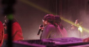 A concert by an African-American group, stylishly dressed women sing into microphone, actively moving rhythmically. Video filming from the stage, concert lighting. Video in 4k, red komodo
