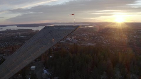 4k drone film of the Holmenkollen ski jump during sunset in Oslo Norway. Oslo city, skyline and Oslo fjord visible in the background. Norwegian landmark