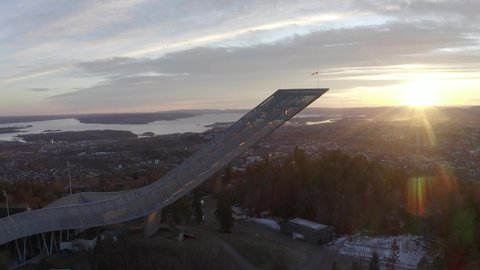 4k drone film of the Holmenkollen ski jump during sunset in Oslo Norway. Oslo city, skyline and Oslo fjord visible in the background. Norwegian landmark