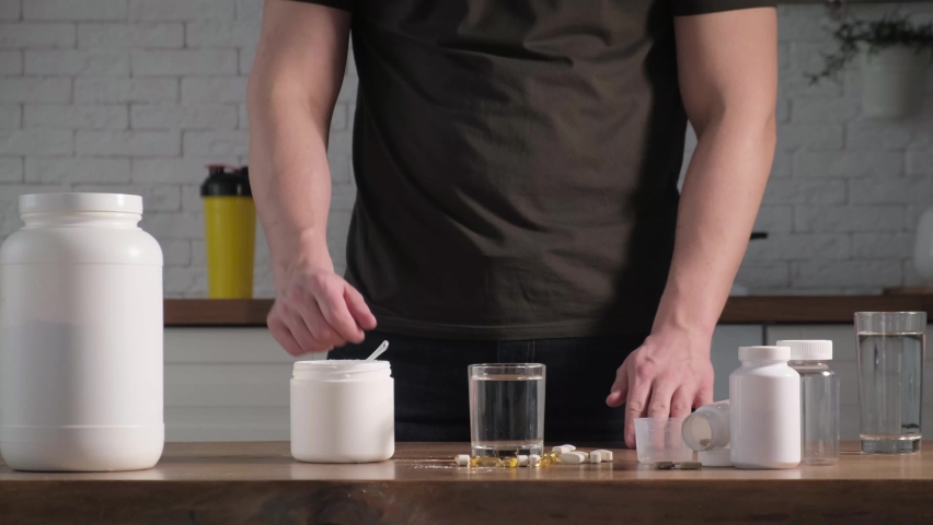A man adds a serving of creatine or aminocysts to a glass of water. Concept: sports supplements, nutrition, bodybuilding, fitness Royalty-Free Stock Footage #1088461711