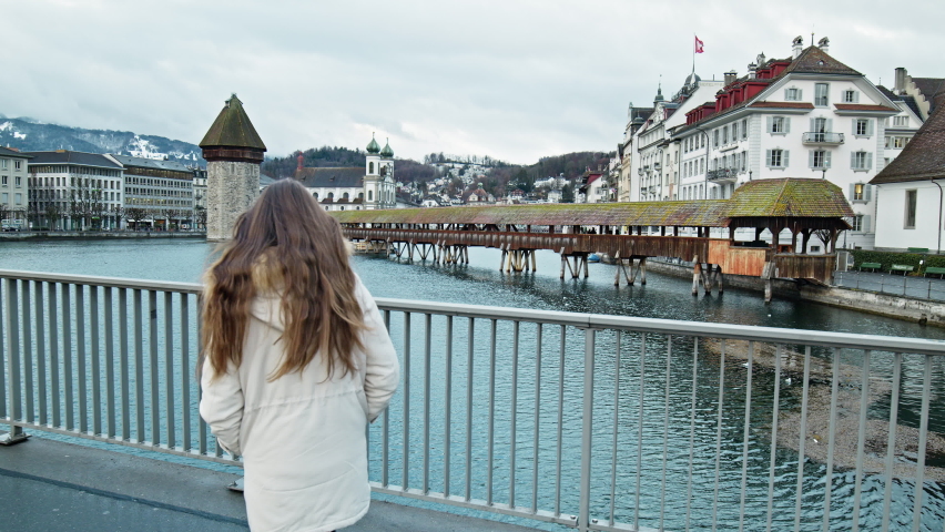 Tourist Girl looking at Chapel Bridge Kapellbrücke, Lucerne, Switzerland. A woman walking and exploring Swiss historical buildings and medieval architecture of an old city in Europe.
