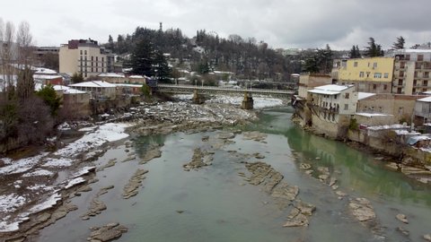 Rioni river with white bridge at cloudy winter day.