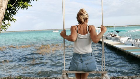 Woman on a swing contemplating beautiful lake 