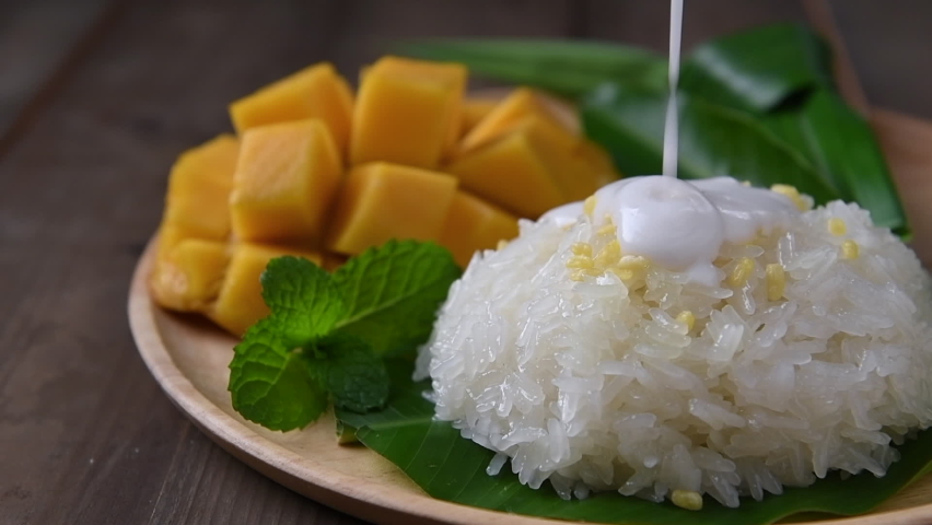 motion of coconut milk on Coconut Flavored Sticky Rice with Ripe Mango on wood dish, 
Popular Thai desserts on summer. Royalty-Free Stock Footage #1088468437