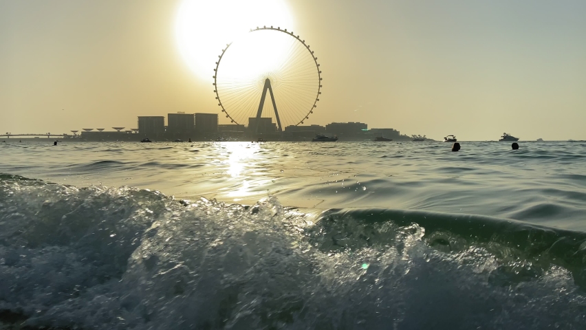 Beautiful landscape of the Persian Gulf. Sea in Dubai at sunset. In the background is a large Ferris wheel. The concept of travel to the united arab emirates. Slow motion. 