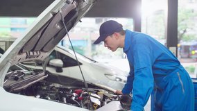 Asian automotive mechanic man open a car hood and check up the engine. Attractive vehicle service manager worker work in mechanics garage, check and maintenance to repair the motorcar car in workshop. - Powered by Shutterstock - Get 15% off with code: PIKWIZARD15