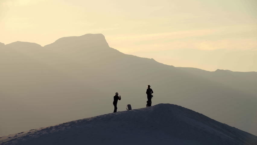 Silhouetted tourists take photos on sand dune at White Sands National Park, 4K