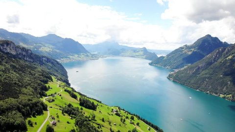 Aerial flyover over the vibrant green shores of Lake Lucerne on a sunny summer day near Seelisberg in Uri, Switzerland