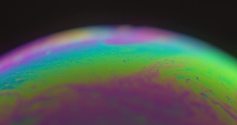 Moving glowing vibrant color patterns forming sphere like alien planet, close up view
