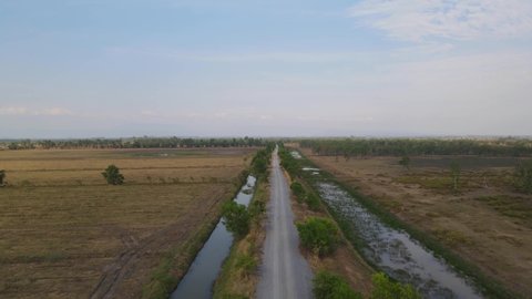 Descending aerial footage revealing this farm road with canals for irrigation, Pak Pli, Nakhon Nayok, Thailand.
