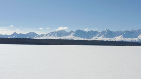 Retiree is out on a sunny day to do cross-country skiing on frozen Pine Lake with a nice view of the Kluane mountains in the Yukon in winter. 