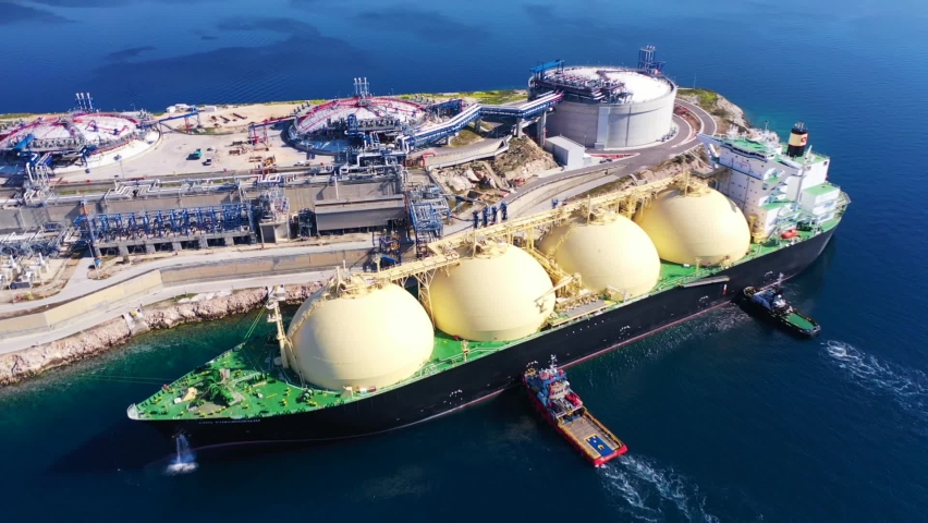Aerial drone video of LNG (Liquified Natural Gas) tanker anchored in small liquefied gas terminal island with tanks for storage Royalty-Free Stock Footage #1088476771