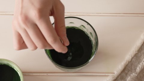 Hand stirring chlorella algae powder in a glass of water, top view