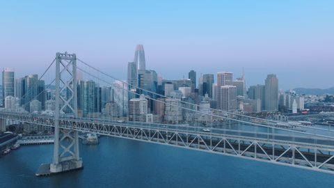 Majestic suspension Bay Bridge on early morning with San Francisco bay view. Establishing aerial view of futuristic skyscrapers in San Francisco downtown, California, United States of America, 4K 