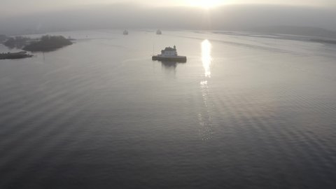 The Oslo fjord and harbor during sunrise. See the spectacular Oslo landmark Dyna fyr, a famous Norwegian lighthouse with 4k drone video. Misty morning over the water. 