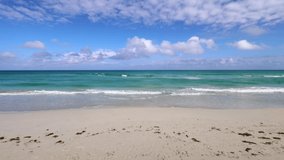 The beautiful beach front of the Cuban beach at Varadero in Cuba showing the waves and clean ocean waters on a sunny summers day with white clouds in the sky filmed in 8k quality