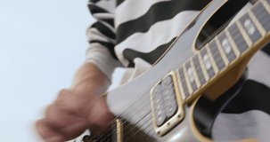 Dynamic video of a musician quickly plucking the strings of a guitar during a performance on the roof. Human hands playing on electric guitar. Fingers on guitar strings.
