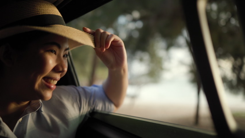 A young beautiful asian woman travel to the sea by car on a bright day. With beautiful blue sky. Vacation holiday weekend after hard work. Sticking her head outta the windshield | Shutterstock HD Video #1088482907