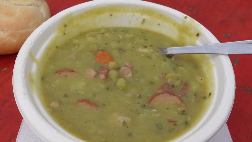 Eating mashed pea soup with sausages. Popular german street food.