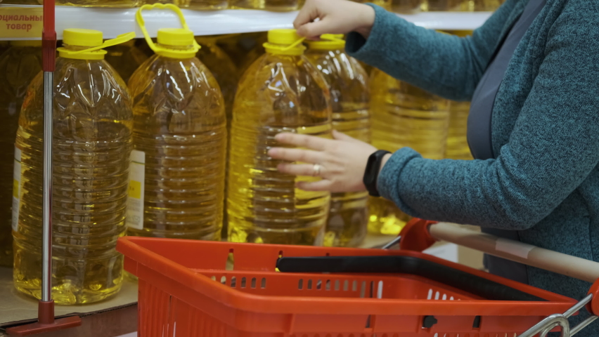 Closeup of Female Buying Big Bottles of Sunflower or Olive Oil, Putting it into Shopping Cart. Hoarding, Economic Crisis and Food Shortage Royalty-Free Stock Footage #1088485101