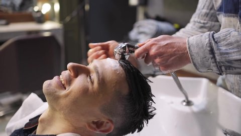 a hairdresser washes the hair of a brunette man in a barbershop. beauty salon for men. scalp and hair care products. men's cosmetics.