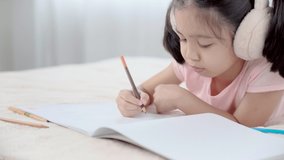 Cute primary school age girls drawing coloring picture with pencils on bed in holiday. Adorable child enjoying creative art hobby activity at home, children development at home concept. 