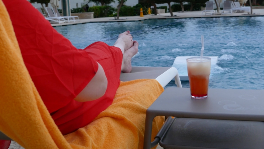 woman drinking the Sex on the beach Cocktail near the swimming pool. Delicious beverages. Holiday and relaxtion concept