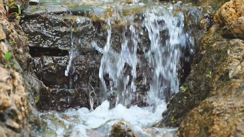 A small artificial waterfall in the park. Selective focus. Soft focus. Slow motion