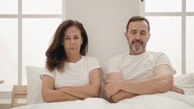 Man and woman couple with serious expression sitting on bed at bedroom - Powered by Shutterstock - Get 15% off with code: PIKWIZARD15