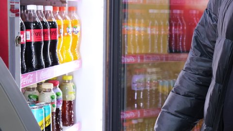 A mans hand in a warm jacket takes Coca-Cola from the refrigerator. March 22, Moscow, Russia 