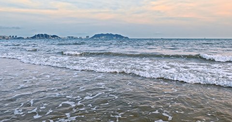 Rolling waves and city skyline in Sanya, Hainan Island, China. Beautiful seascape. famous resort in china.