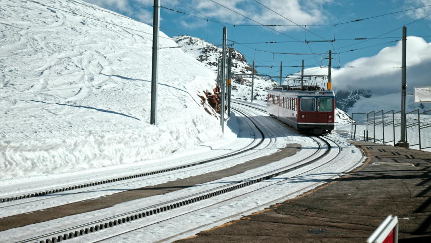 Beautiful Matterhorn Red Swiss Train Driving up the hill in Zermatt, Switzerland. National Train transporting passengers in the Swiss Alps in the Winter with white Snow.