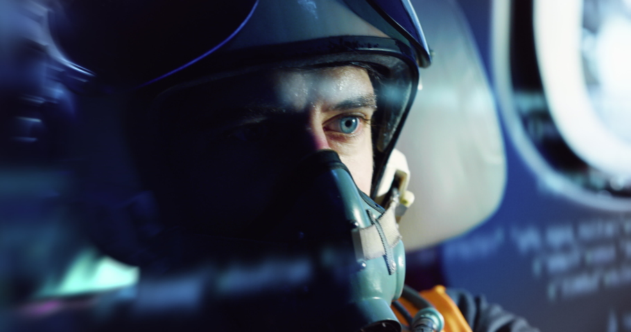 Close up shot of determined military armed forces soldier or pilot wearing protective helmet and oxygen mask inside cockpit of fighter jet airplane during aviation warfare or flight training routine.
