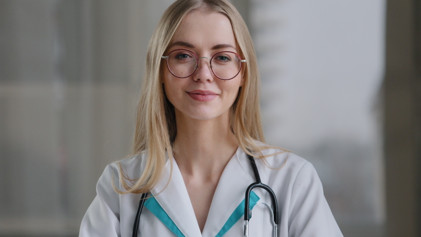 Caucasian doctor specialist nurse woman practitioner therapist in glasses in clinic hospital at table shows heart shape sign of mercy love kindness assistance medicine help international medical day Royalty-Free Stock Footage #1088503141