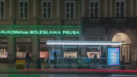 Warsaw, Poland - 04.12.2021: timelapse people are waiting for bus at public transport stop in historic city center in evening