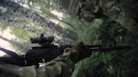 Close-up action shot, armed special forces soldiers with Kalashnikov assault rifles on a special operation in a dense deciduous forest protect the front line. Soldiers in full uniform