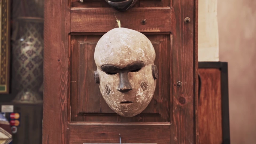 Ancient African mask hanging on wooden door in antique boutique store