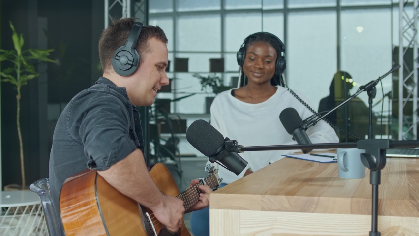 African American Presenter is Broadcasting Live. An Influential Musician Sings and Plays the Guitar During a Radio Broadcast in the Studio. Online Radio Concept.