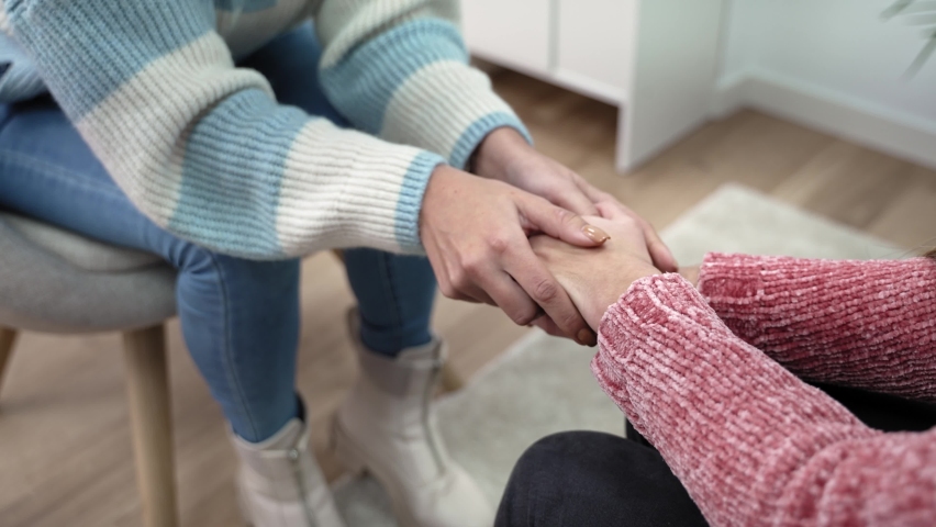 Hands of nervous anxious teenager girl attending mental therapy with counselor. Female Therapist holding hands of young woman offering help and support | Shutterstock HD Video #1088511603