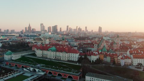 Establishing Aerial Panorama of Warsaw City Skyline. Typical Old Town with Landmark Red Roofs and Downtown Business District with Skyscrapers at Sunset. 4K scenic panoramic shot of Capital of Poland