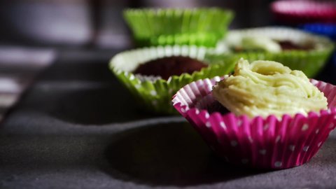 Decorating cupcakes with icing and piping bag close up dolly slow motion shot selective focus