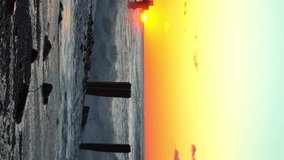 Storm waves crash against old reinforced concrete pillars on the beach against the background of a colorful and red orange sunset, a storm at sea. vertical video, slow motion - Powered by Shutterstock - Get 15% off with code: PIKWIZARD15