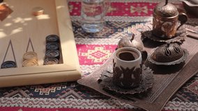 Traditional Turkish cafe, freshly brewed coffee in traditional cups, sunlight on the table, 4K live video. Playing backgammon in a cafe, rest.