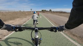 4k slow motion video of two little boys riding with their father on a bike path